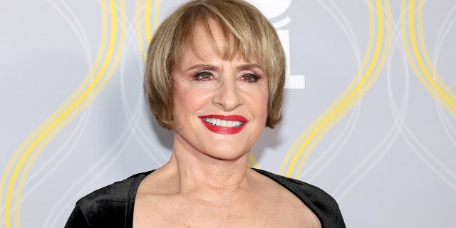 Patti LuPone smiles on the Tony Awards red carpet in a square cut, black dress and red lipstick