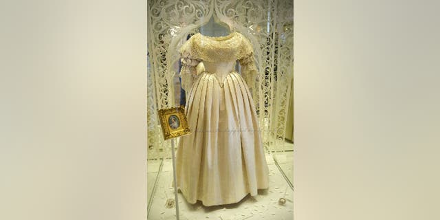 Queen Victoria's wedding dress encased in glass display case during an exhibition.