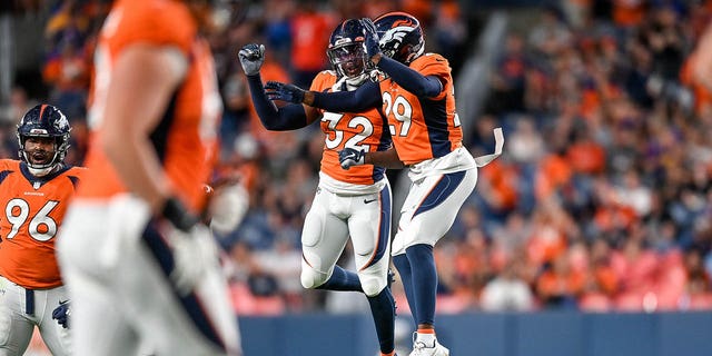 Safety Delarrin Turner-Yell #32 and cornerback Faion Hicks #29 of the Denver Broncos celebrate after a Turner-Yell sack on fourth down in the fourth quarter of a preseason NFL game against the Minnesota Vikings at Empower Field at Mile High on August 27, 2022 in Denver, Colorado. 