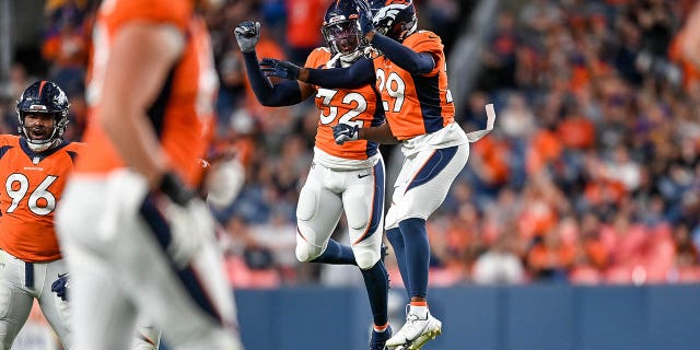 Safety Delarrin Turner-Yell #32 and cornerback Faion Hicks #29 of the Denver Broncos celebrate after a Turner-Yell sack on fourth down in the fourth quarter of a preseason NFL game against the Minnesota Vikings at Empower Field at Mile High on August 27, 2022 in Denver, Colorado.
