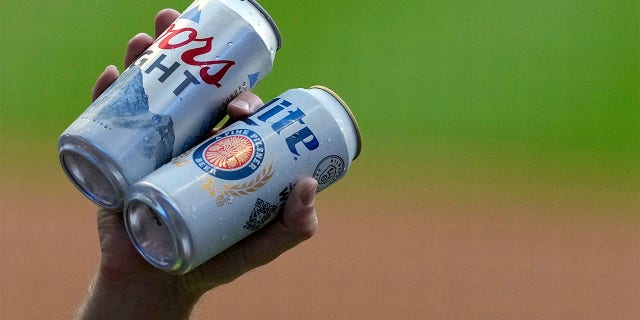 Un vendedor sostiene latas de Coors Light y Miller Lite durante un juego entre los Toronto Blue Jays y los Brewers en el American Family Field el 24 de junio de 2022 en Milwaukee.