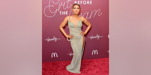 Toni Braxton has both hands on her hips in a light teal tank top with a sparkly draped skirt over it on the red carpet