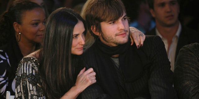 Demi Moore throws her arm around Ashton Kutcher at a fashion show