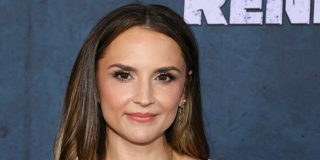 Rachael Leigh Cook soft smiles on the red carpet in a bubblegum pink dress with thick straps