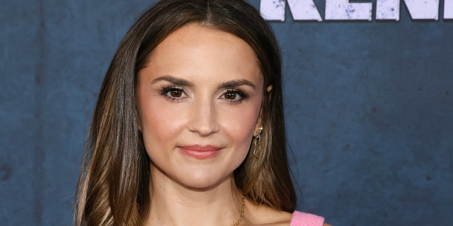 Rachael Leigh Cook soft smiles on the red carpet in a bubblegum pink dress with thick straps