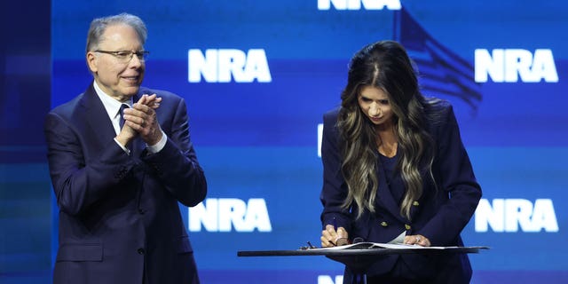 With NRA Executive Vice President and CEO Wayne LaPierre by her side, South Dakota Governor Kristi Noem signs an executive order to protect gun rights in her state at the 2023 NRA-ILA Leadership Forum on April 14, 2023, in Indianapolis, Indiana.