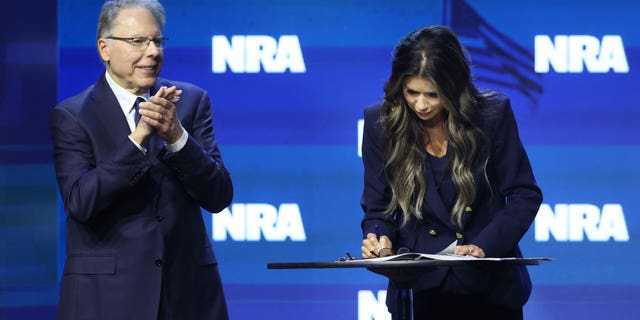 With NRA Executive Vice President and CEO Wayne LaPierre by her side, South Dakota Governor Kristi Noem signs an executive order to protect gun rights in her state at the 2023 NRA-ILA Leadership Forum on April 14, 2023, in Indianapolis, Indiana.