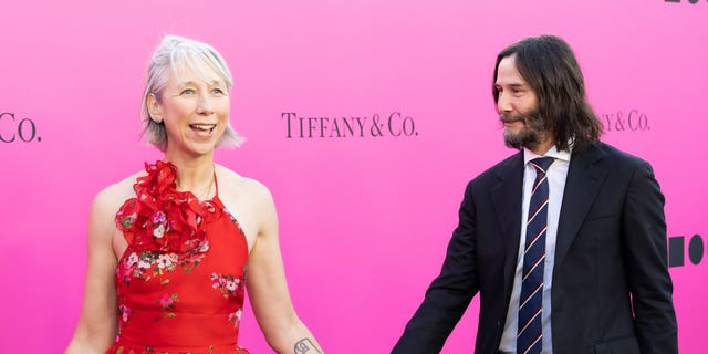 Keanue Reeves donned a two-piece black suit with a white collared button-down underneath while Alexandra Grant stunned in a red flowing floral dress.