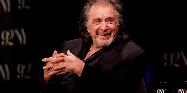 AL Pacino in a black suit on sitting in a chair on stage.
