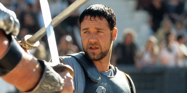 Russell Crowe in "Gladiator" with armor on holding up a sword, close up of his face
