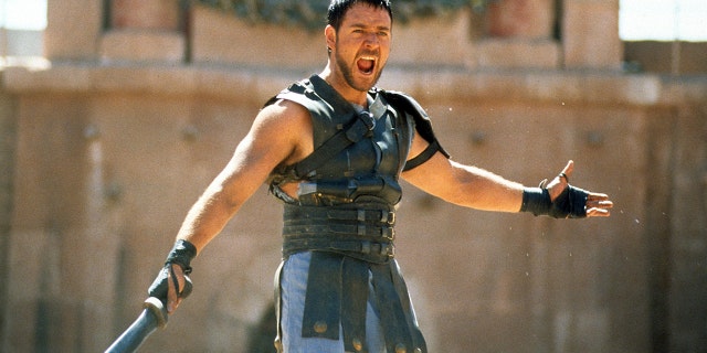 Russel Crowe yells with body armor on holding a sword in a scene from "Gladiator"