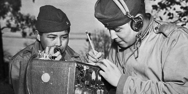 A two-man team of Navajo Code Talkers attached to a Marine regiment in the Pacific relay orders over the field radio using their native language.