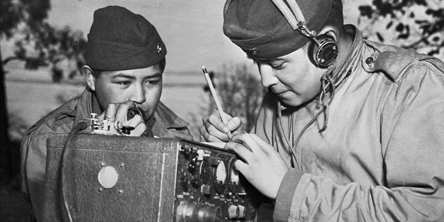 A two-man team of Navajo Code Talkers attached to a Marine regiment in the Pacific relay orders over the field radio using their native language.