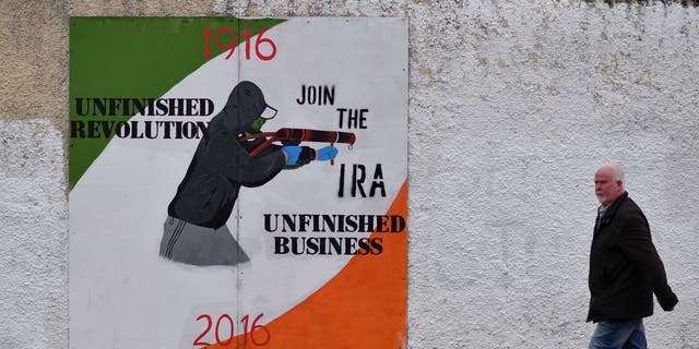 FILE PHOTO: A man walks past a dissident republican mural in the Bogside area of Derry, Northern Ireland. 