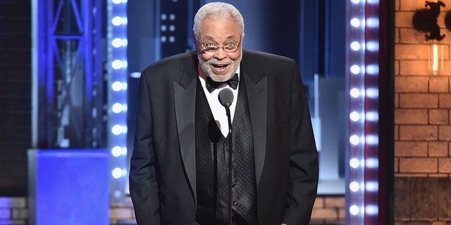 James Earl Jones hunches over slightly at the Tony Awards in a classic black tuxedo as he speaks into a microphone