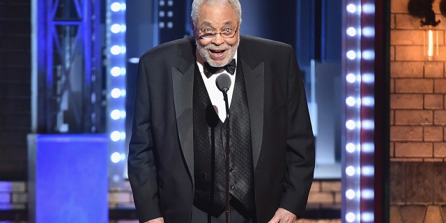 James Earl Jones hunches over slightly at the Tony Awards in a classic black tuxedo as he speaks into a microphone