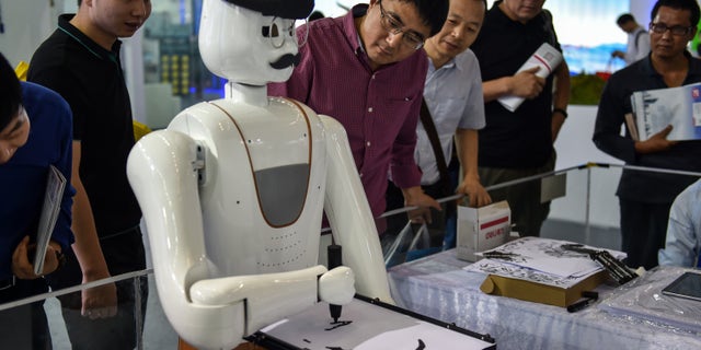 İzleyiciler, 16 Kasım 2017'de Çin'in Shenzhen kentinde bir robotun resim çizdiğini gözlemliyor.