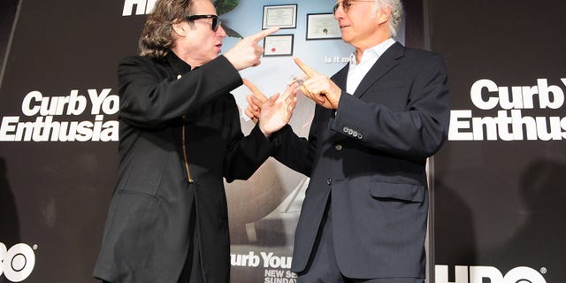 Richard Lewis and Larry David laughing and pointing at each other on the red carpet