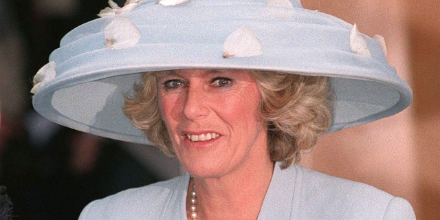 Camilla Parker Bowles in a blue dress with an oversized matching hat adorned with flowers