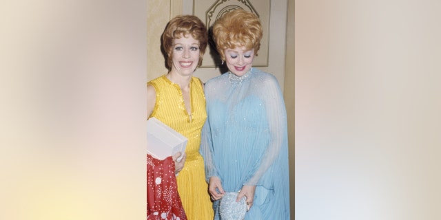 Carol Burnett wearing a yellow dress next to Lucille Ball wearing a blue dress