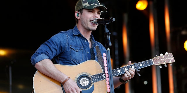 Granger Smith performing on stage wearing a denim shirt while holding a guitar
