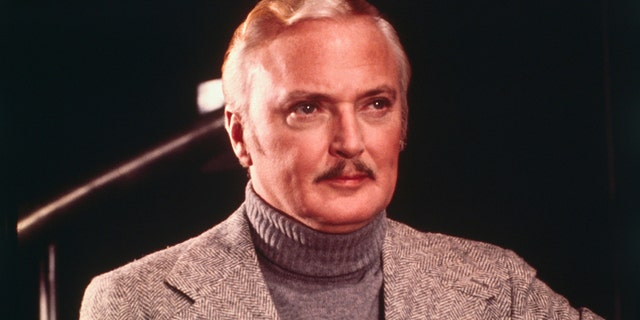 A close-up of Jack Cassidy in a grey blazer and matching turtleneck