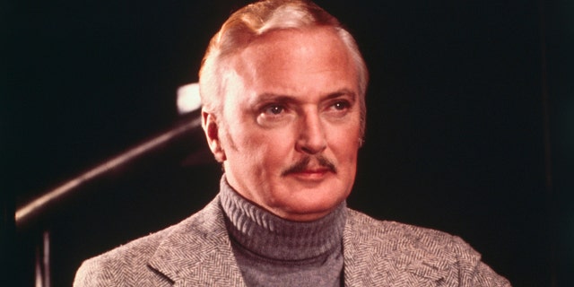 A close-up of Jack Cassidy in a grey blazer and matching turtleneck