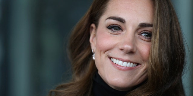A close-up of Kate Middleton smiling wearing a black turleneck