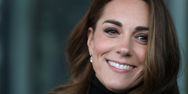 A close-up of Kate Middleton smiling wearing a black turleneck