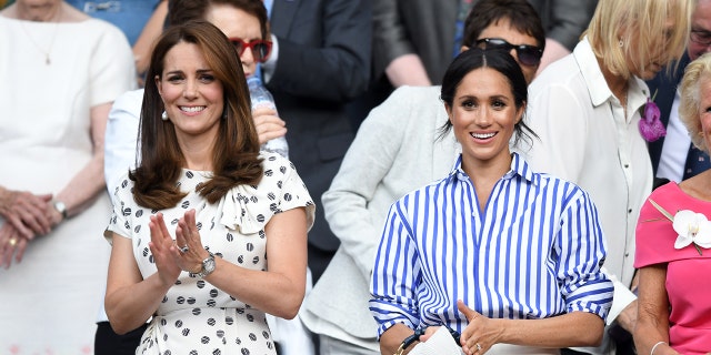 Kate Middleton wearing a white printed dress next to Meghan Markle wearing a blue and white striped blouse holding a wide brimmed hat