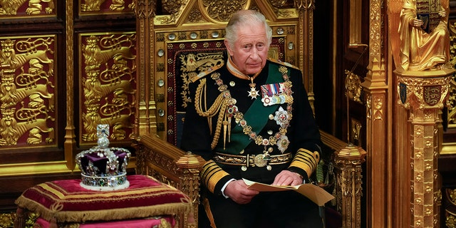 King Charles in royal regalia seated on a throne next to a crown