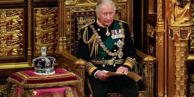 King Charles in royal regalia seated on a throne next to a crown