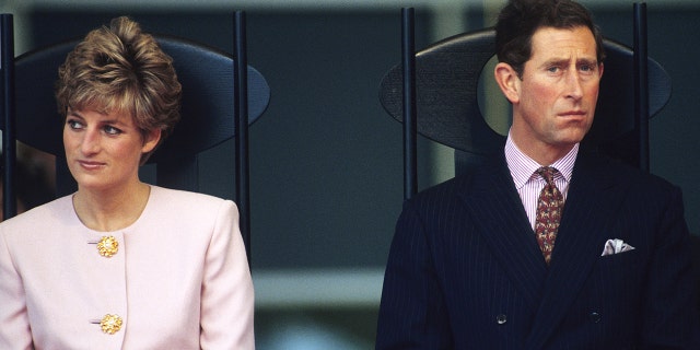 Princess Diana wearing a pink blazer top next to Charles in a suit and tie