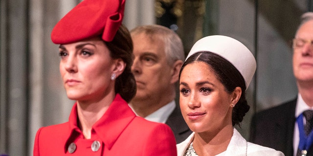 A close-up of Kate Middleton in a red dress and a matching hat next to Meghan Markle in a white dress with a matching hat