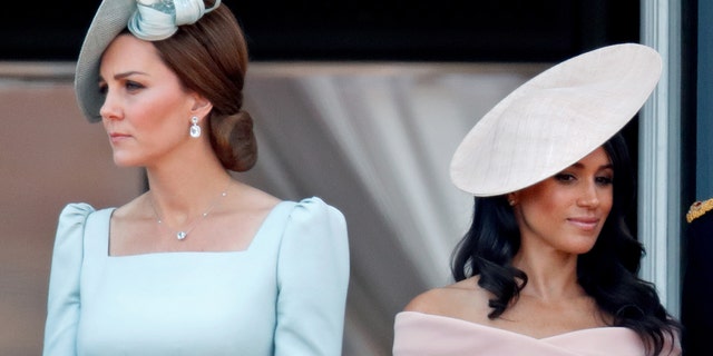 Kate Middleton wearing a light blue dress next to Meghan Markle wearing a pink dress