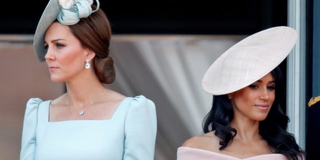 Kate Middleton wearing a light blue dress next to Meghan Markle wearing a pink dress