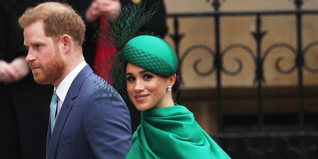 Meghan Markle wearing a bright green dress with a matching hat walking alongside Prince Harry in a suit