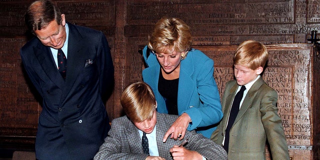 Princess Diana pointing at Prince Williams book while Prince Harry and Prince Charles watch on