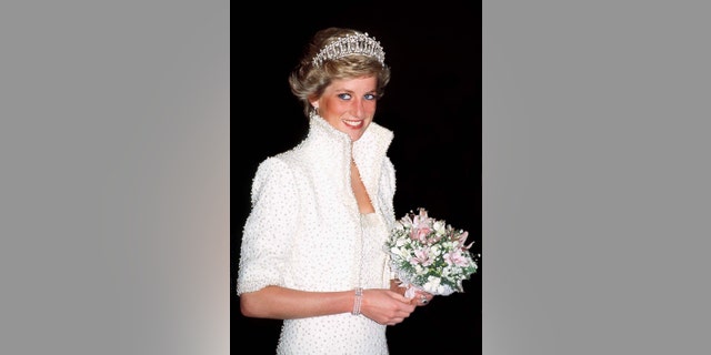 Princess Diana in a white dress and a tiara holding a bouquet of flowers