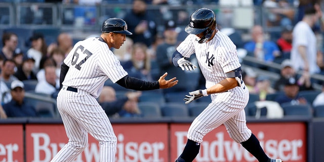 Giancarlo Stanton #27 celebrates with New York Yankees third base coach Luis Rojas #67 after hitting a solo home run during the third inning against the San Francisco Giants at Yankee Stadium on April 1, 2023 in the district of the Bronx of New York City.