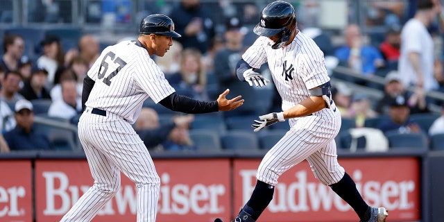Giancarlo Stanton #27 celebrates with third base coach Luis Rojas #67 of the New York Yankees after hitting a solo home run during the third inning against the San Francisco Giants at Yankee Stadium on April 01, 2023 in the Bronx borough of New York City.