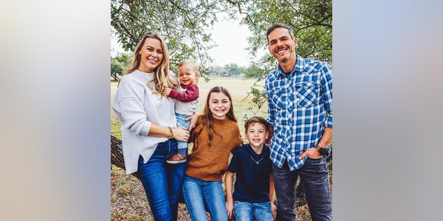 Granger Smith, his wife and their three children posing outside for a family photo