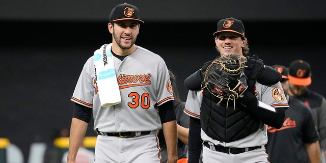 Grayson Rodriguez #30 of the Baltimore Orioles and Adley Rutschman #35 walk back to the dugout ahead of Rodriguez' Major League debut game against the Texas Rangers  at Globe Life Field on April 05, 2023, in Arlington, Texas.