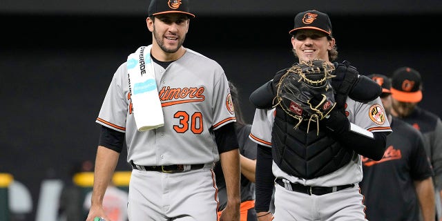 Grayson Rodriguez #30 of the Baltimore Orioles and Adley Rutschman #35 return to the dugout prior to Rodriguez's Major League debut against the Texas Rangers at Globe Life Field on April 5, 2023 in Arlington, Texas.