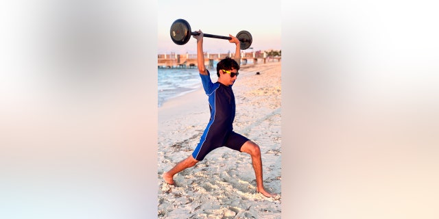 Heather Arak son lifting weight on beach