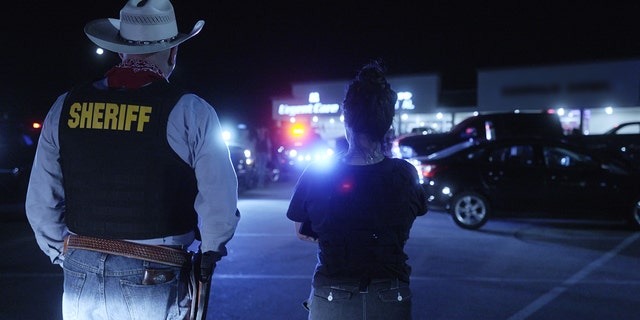 Roo Powell standing next to a sheriff at night