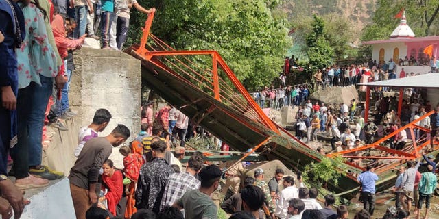 La gente se aglomera cerca de una pasarela de acero que se derrumbó durante la feria Baisakhi en Udhampur, cerca de Jammu, India, el 14 de abril de 2023.