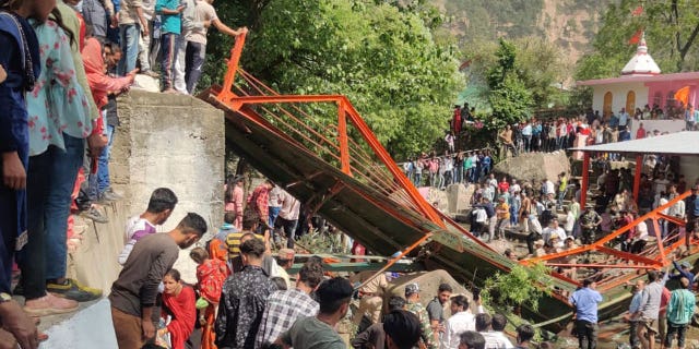 Una niña murió y al menos 70 resultaron heridas al derrumbarse un puente en Cachemira 4 La gente se aglomera cerca de una pasarela de acero que se derrumbó durante la feria Baisakhi en Udhampur, cerca de Jammu, India, el 14 de abril de 2023.