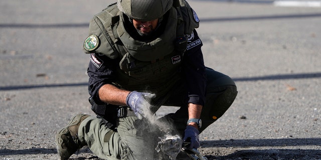An Israeli police officer removes remains of an intercepted rocket fired from Lebanon that fell in Shlomi, northern Israel Thursday, April 6, 2023. Israeli air defenses intercepted a rocket fired from Lebanon into northern Israel, the Israeli military said. It was not immediately clear who was behind the rare rocket fire from Lebanon.