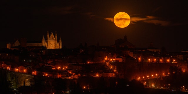 The full moon rises next to Orvieto Cathedral (Duomo di Orvieto church), Umbria, Italy, on April 6, 2023. April's full moon is also known as the pink, egg or fish moon. 